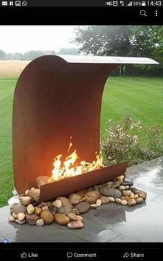 an outdoor fire pit with rocks on the ground and grass in the backround