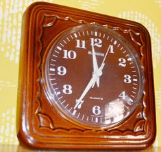 an old fashioned wooden clock on a yellow and white wallpapered background with the time at 11 00