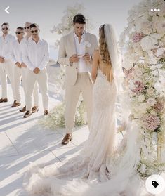 the bride and groom are standing in front of their wedding party, all dressed in white