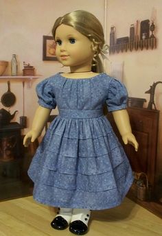 the doll is wearing a blue dress and black shoes