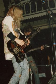 two men are playing bass guitars on stage