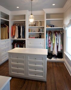 a walk in closet with white cabinets and drawers