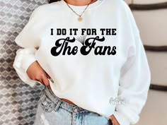 a woman wearing a sweatshirt that says i do it for the fans in black letters