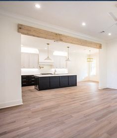 an empty kitchen and living room with hard wood flooring, white walls and ceiling fan