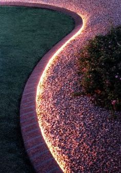 a garden path lit up with lights in the grass and gravel between two lawn areas