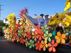 people are riding in the back of a float decorated with flowers and leaves on it