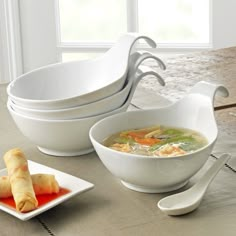 two white bowls filled with soup sitting next to each other on a table near a window