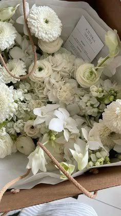 a bouquet of white flowers in a box with twine and string tied around it