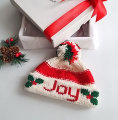 a knitted christmas hat with the word joy on it next to a white box