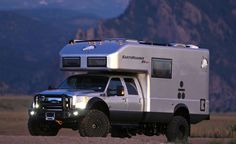 a truck with a camper attached to it's bed parked in the desert