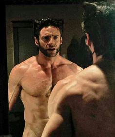 a shirtless man looking at himself in the mirror