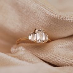 an engagement ring with three baguettes on it sitting on top of a blanket