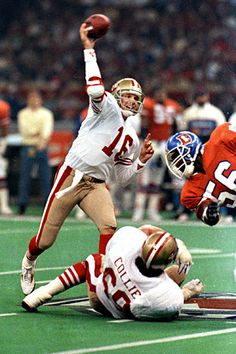 two football players are on the field during a game with an opposing player in mid air