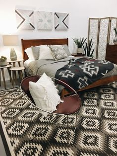 a bed sitting on top of a rug next to a table with pillows and blankets