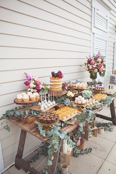 a table with cakes and cupcakes on it in front of a white house