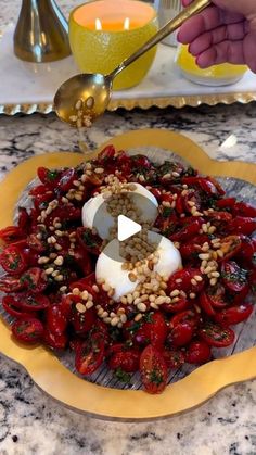 a plate with tomatoes and other vegetables on it, being spooned into the bowl