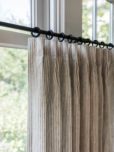 a curtain with black metal rods hanging from it's side in front of a window