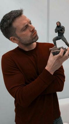 a man holding a small figurine in his hand and looking at the camera