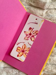 an open pink book with flowers on the front and back cover sitting on a bed