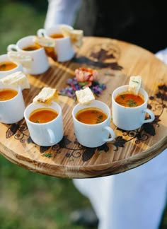 several cups of soup on a wooden tray