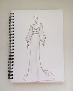 a drawing of a woman's dress on top of a notepad with a pen