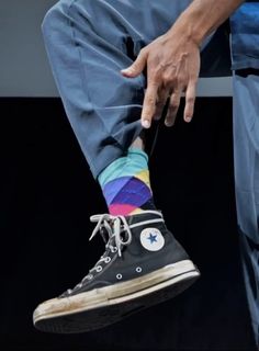 a person sitting down with their foot in the air and wearing colorful socks that are tied to them