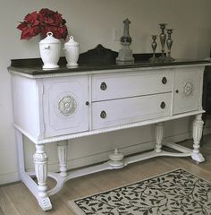 a white dresser with two vases on top of it and a rug in front of it