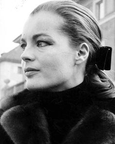 a black and white photo of a woman wearing a fur coat with a bow in her hair