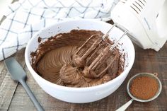 a bowl filled with chocolate frosting next to a mixer