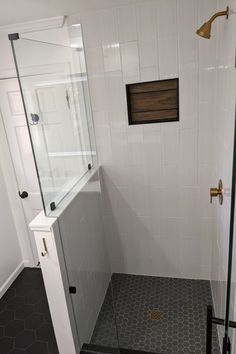 a bathroom with a walk in shower next to a white tiled wall and black floor