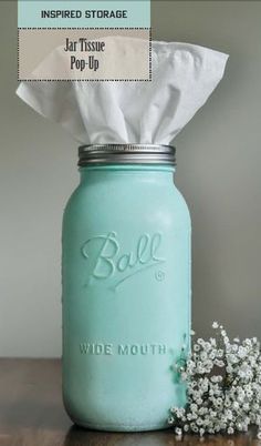 a blue mason jar sitting on top of a wooden table next to a tissue dispenser