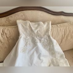 a white dress sitting on top of a couch next to a wooden headboard and pillow