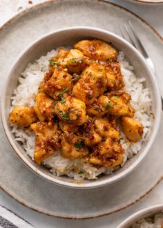 a white bowl filled with rice and chicken on top of a table next to silverware