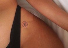 a woman laying in bed with a tattoo on her stomach and the back of her body