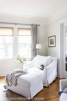 a living room with white furniture and windows