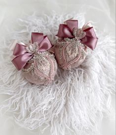 two baby shoes with bows on them sitting on a white fur covered floor next to each other