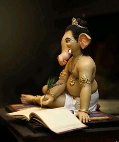 a statue of an elephant sitting on top of a table next to a open book