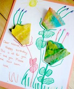 three different colored paper flowers sitting on top of a piece of paper