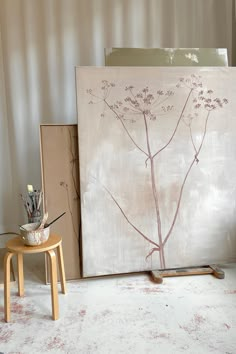 a painting is sitting on the floor next to a small table and chair with pens in it