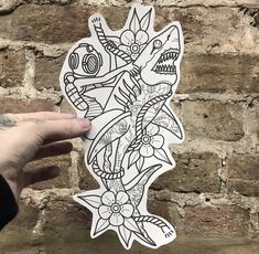 a hand holding up a sticker with an image of a fish and flowers on it