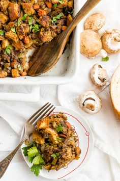 a casserole dish with mushrooms and parsley on the side next to a fork