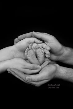 two hands holding a baby's foot in black and white