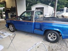 a blue pick up truck parked in front of a garage