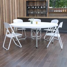 a white table with four chairs around it on a hard wood floor next to a bar