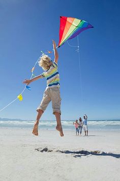 a young boy flying a kite on the beach