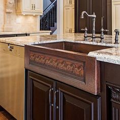 a kitchen with marble counter tops and wooden cabinets, along with stainless steel dishwashers