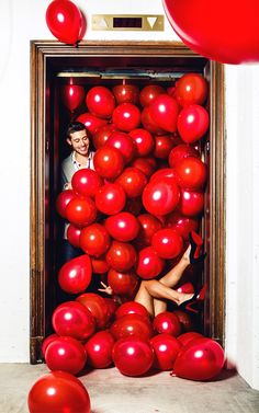 a man and woman are surrounded by red balloons in an old wooden framed photo frame