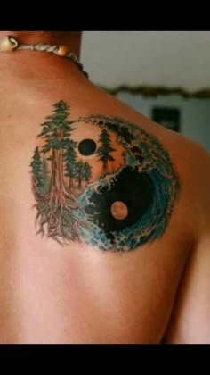 a man with a tattoo on his back has a tree and yin - yang symbol