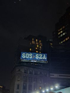 the scoreboard is lit up at night in front of tall buildings and skyscrapers