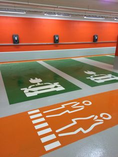 an orange and green parking garage with signs on the floor